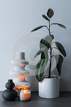 White and black decorative handmade vase and burning candle on a background of gray wall interior decoration. Home interior with