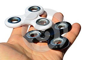 White and black fidget spinner toys held in palm of adult male person, white background
