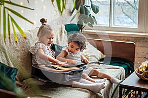 white and black girls on a couch and plays the guitar. babes is playing, composes melody and music. photo