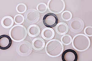 White and black hydraulic and pneumatic o-ring seals of different sizes scattered a white background.