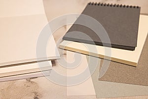 white and black notebook, color sheets on gray background