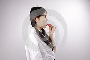 Close up white blank background Asian Chinese girl young woman is eating fruit Strawberry healthy balanced life