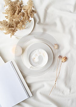 white blank book with cup of coffee and burning candle , cozy composition with opened book mockup