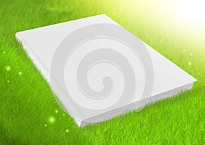 White blank book in green grass
