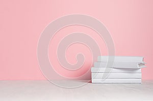 White blank books on white shelf and soft pink wall as modern, elegant home decor.