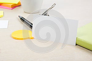 White blank business card. Office table desk with set of colorful supplies, cup, pen, pencils, flower, notes, cards on