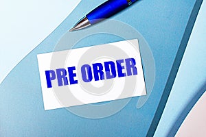 White blank card with PRE ORDER text and blue pen on blue, cyan and pink background