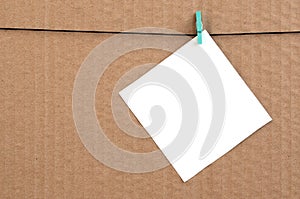 White blank card on rope on a brown cardboard background. Creati