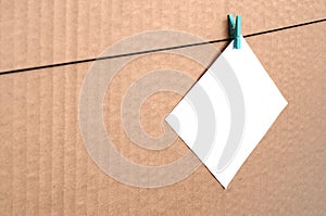 White blank card on rope on a brown cardboard background. Creati