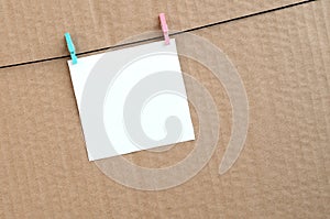 White blank card on rope on a brown cardboard background. Creati