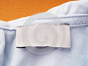 White blank label on the inside of the garment, on the neck, close-up. empty tag for sizes and company name on clothing