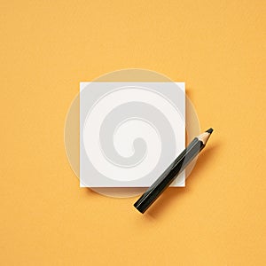 White blank memo notepad and pencil on orange desk background. top view, copy space