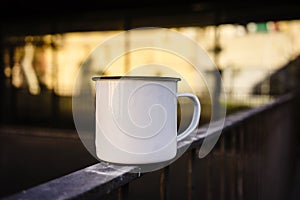 White and blank metal tea cup on the rails. Blurred background. 3d rendering