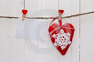 White blank paper card with heart hanging on white wooden painted boards.