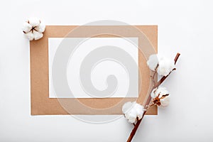 White blank paper invitation card mockup with dry bloom cotton flowers branch on flat lay. Modern desktop mock up for