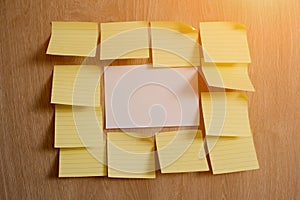 White blank piece of paper on a wooden texture background surrounded with yellow blank notes