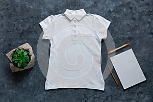 White blank polo t-shirt and notebook mockup on dark background. Kids school Casual clothes with sketchbook template