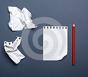 white blank sheets in a line from a notepad and red wooden pencil