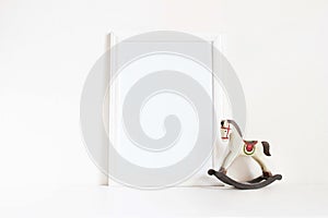 White blank wooden frame mockup with old wooden horse toy on the white table. Styled stock feminine photography. Home