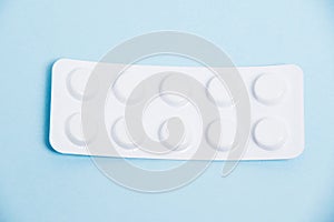 White blister pack with antibiotic pills on blue paper background, top view