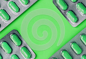 White blister pack of tablets pill statins for light resistance packaging on green background. Green tablets photo