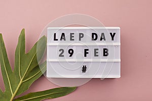 White block calendar present date 29 and month February and plant on pink background. Leap day