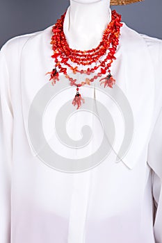 White blouse and red necklace on mannequin.