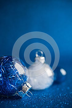 White and blue christmas ornaments on dark blue glitter background with space for text.