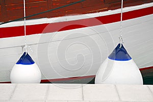 White with blue fenders protecting the side of a sailing vessel as it heads into port.