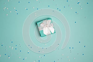 White and blue flowers with gift box on mint background and copy space.