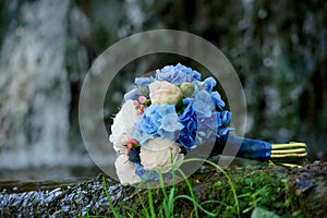 White and blue flowers wedding bouquet on a waterfall background