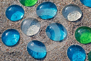 White, blue and green glass beads on sand