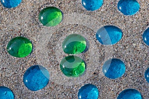 White, blue and green glass beads on sand