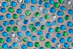 White, blue and green glass beads on sand