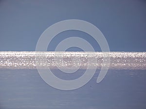 White, blue and grey bokeh effect and purposely blurred view of sea or ocean landscape. Blurry and shiny water and sky background