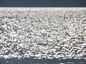 White, blue and grey bokeh effect and purposely blurred view of sea or ocean landscape. Blurry and shiny water and sky background