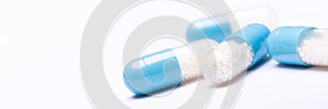 White and blue medication capsules on white background. Medication and prescription pills web banner.