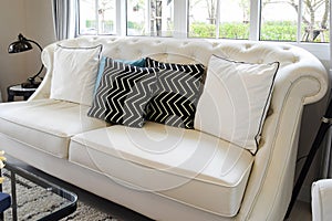 White and blue pillows on a white leather couch in living room