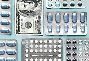 White and blue pills in blister with money dollar on a blue background, medicine flat lay