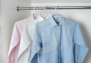 White, blue and pink clean ironed men's shirts hanging on hanger