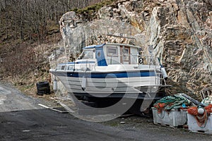 White and blue plastic fishing boat laid up by a road..