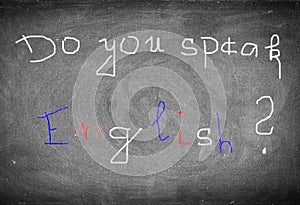 White, blue and red inscription Do you speak English? on old black chalkboard.