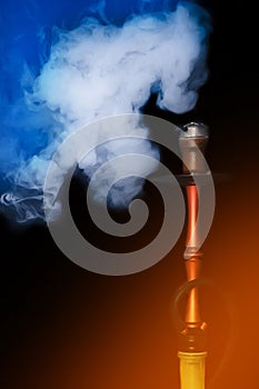 White blue smoke smoker cloud from hookah clay head pipe object on black and orange light background
