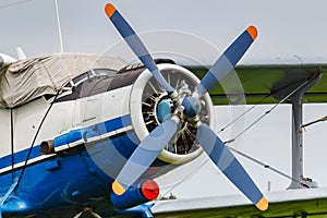 White and blue soviet aircraft biplane Antonov AN-2 at the parking on airfield closeup against cloudy sky