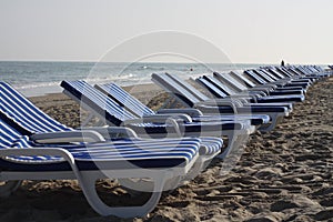 white and blue striped chairs on the beach