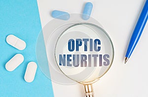 On a white and blue surface are pills, a pen and a magnifying glass with the inscription - Optic neuritis