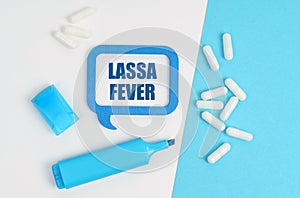 On a white and blue table are pills, a marker and a blue plaque with the inscription - Lassa fever