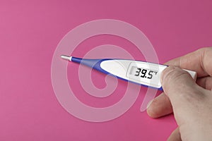 White-blue thermometer with a high temperature of 39.5 degrees Celsius in hand