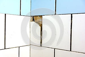 White and blue tiles on the wall. Old and broken tiles require replacement. Abstract background