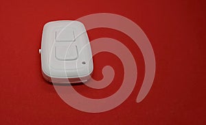 White bluetooth remote control camera shutter for smartphone, isolated on the red background.